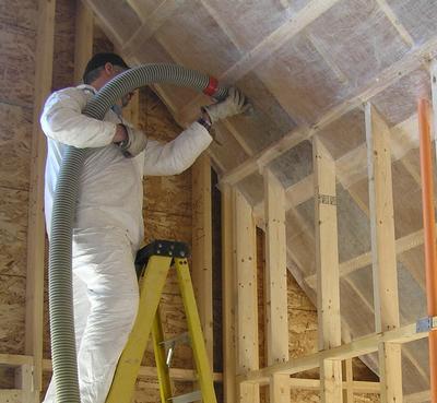 man holding hose spraying cellulose into walls